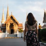 Voyageuse en tenue couvrant les épaules devant un temple thaïlandais